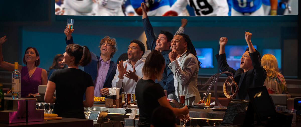 A group of friends cheering and watching TV at The League Sports Bar