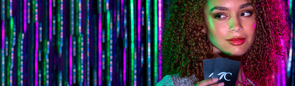 Woman holding Choctaw-branded playing cards against a neon-striped backdrop.