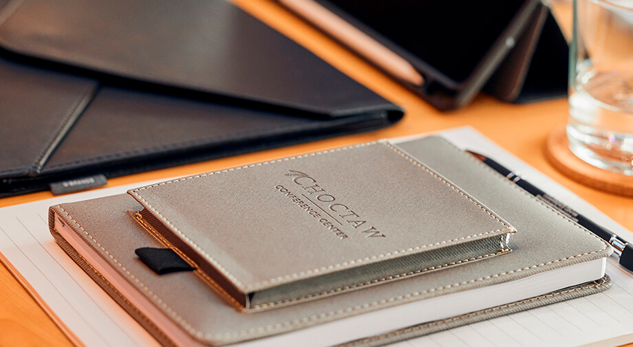 Choctaw Conference Center branded notepad and pen on a meeting table beside a leather folio.