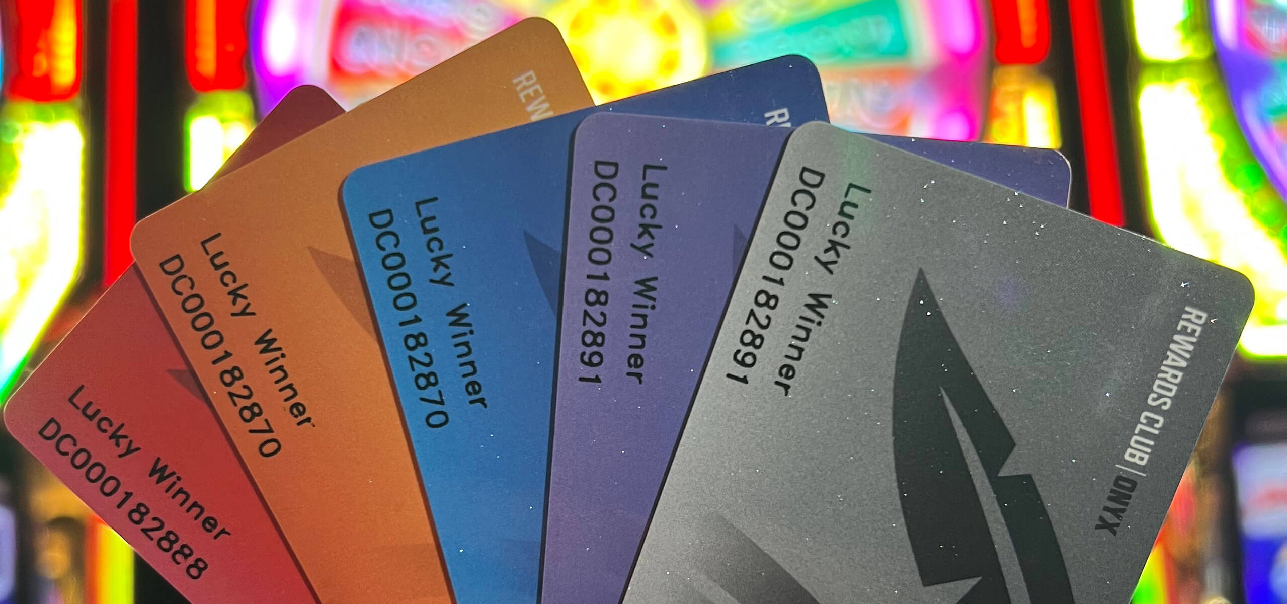 Several Choctaw Rewards Club cards in multiple tiers and colors held up against bright slot-machine lights