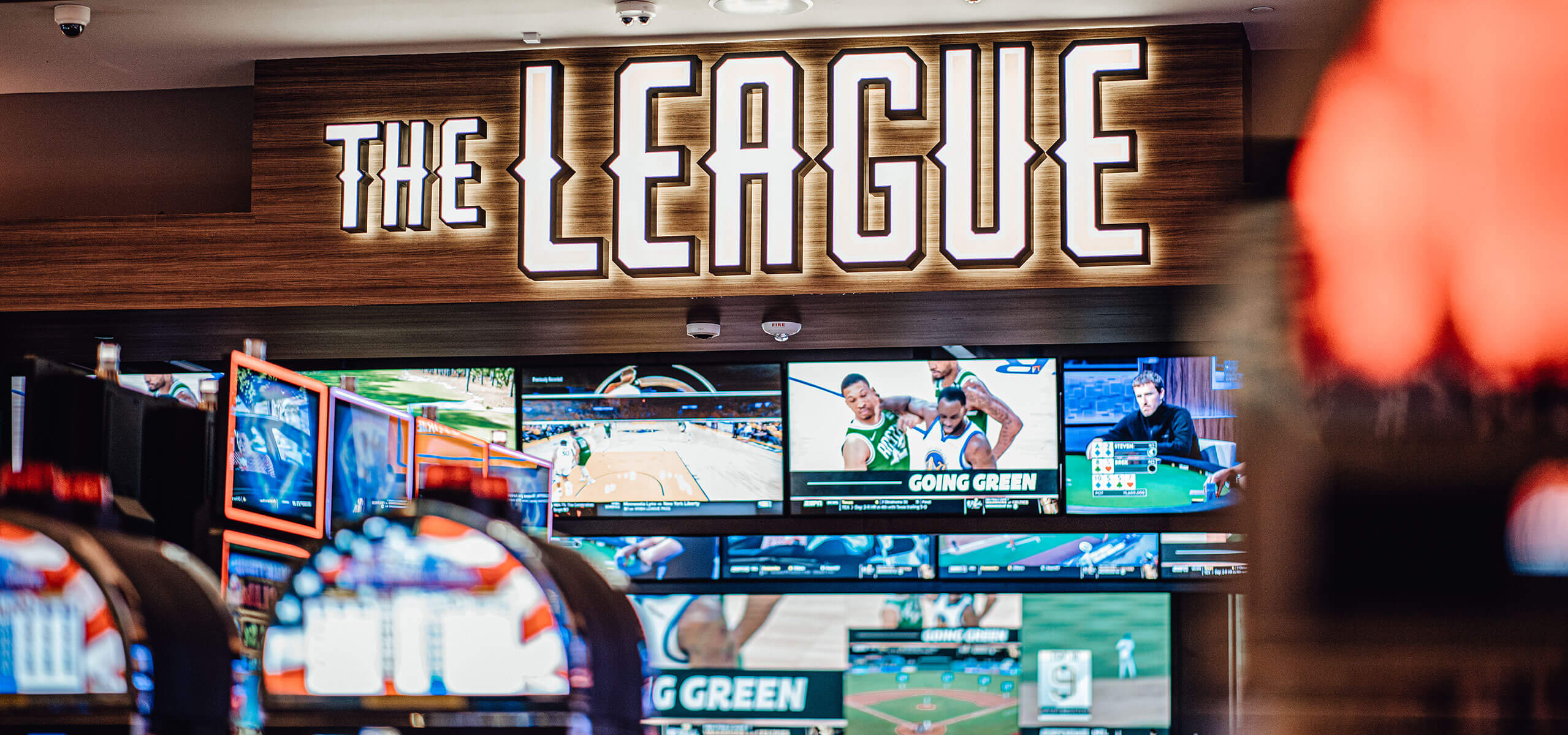 The League sports bar with a wide wall of TVs, sleek bar counter, high-top tables, and neon accent lighting