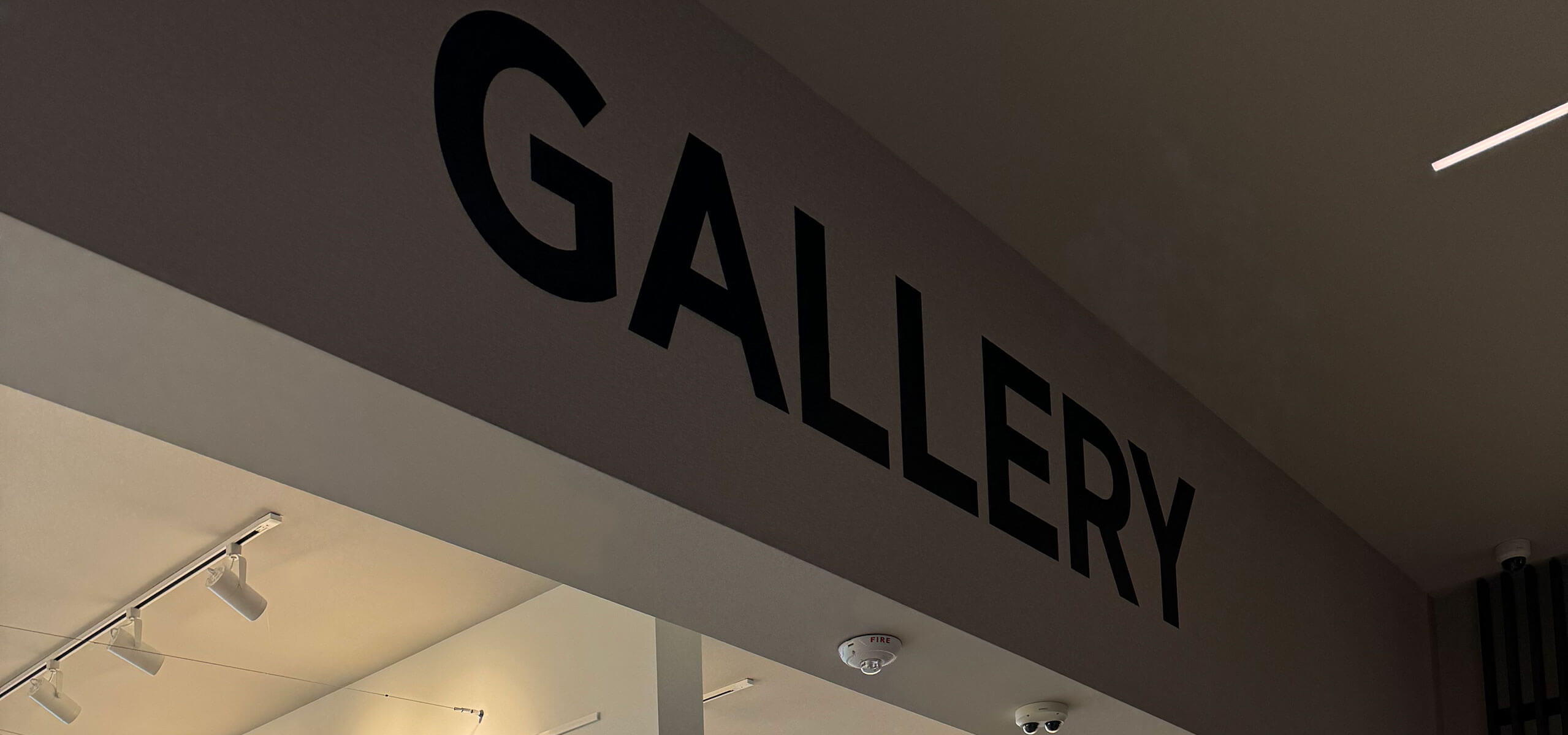 Entrance to the Women’s Art Gallery—bold ‘GALLERY’ lettering across the beam with ceiling track lights below.