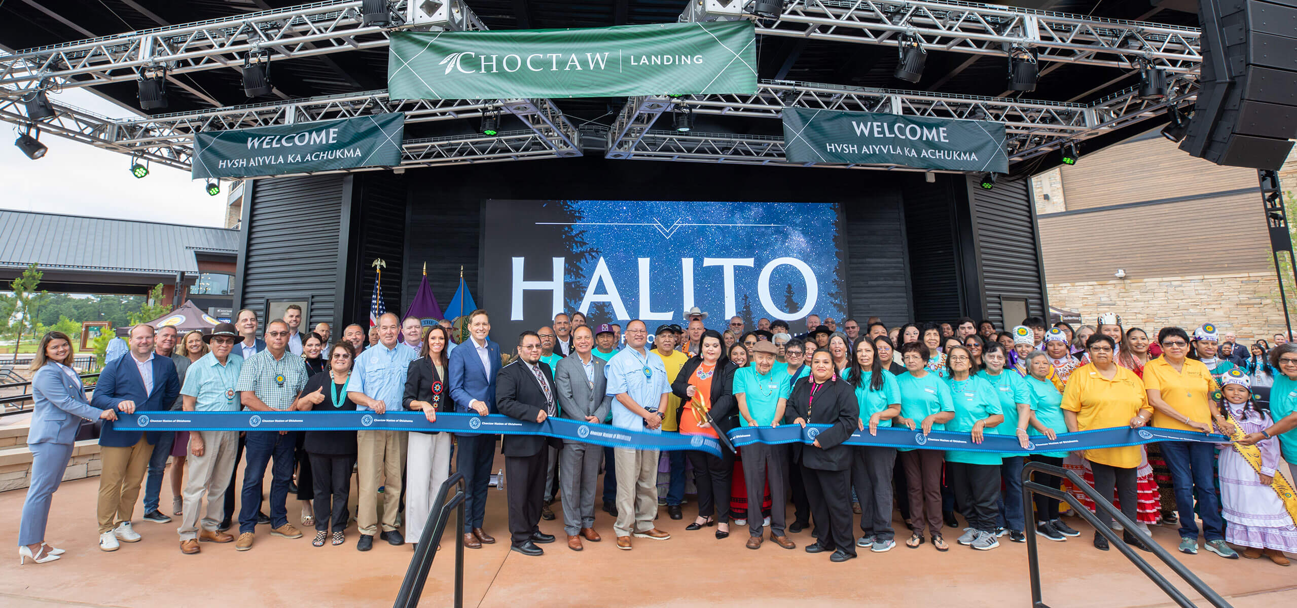 Large group ribbon-cutting on an outdoor stage for Choctaw Landing