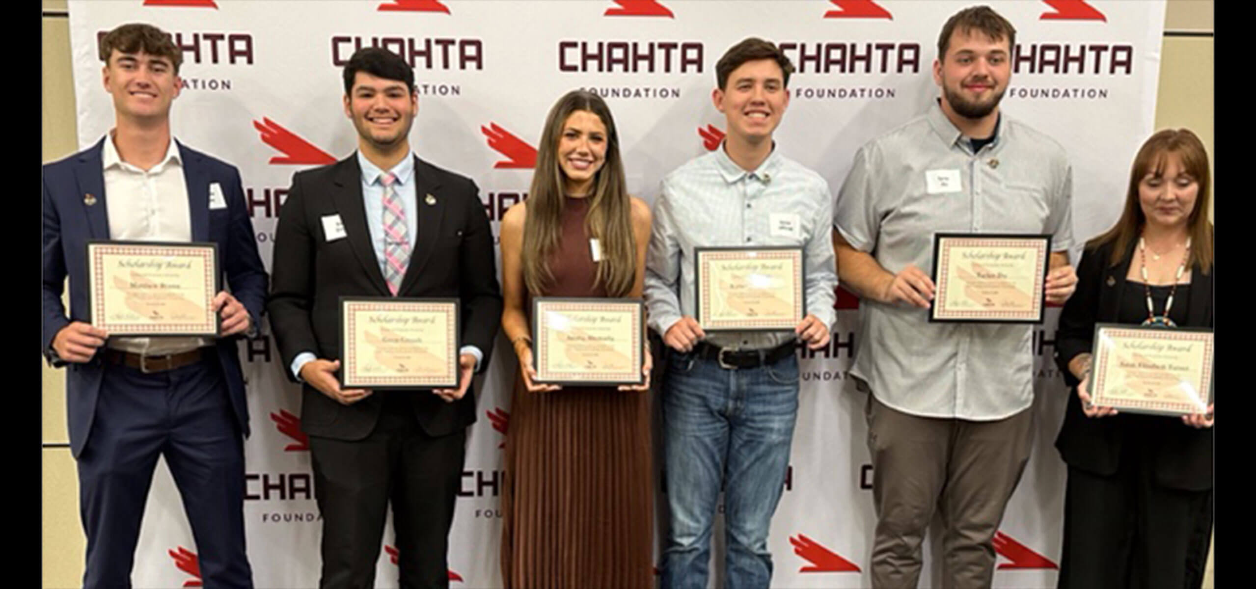 Six scholarship recipients holding certificates in front of a Chahta Foundation backdrop