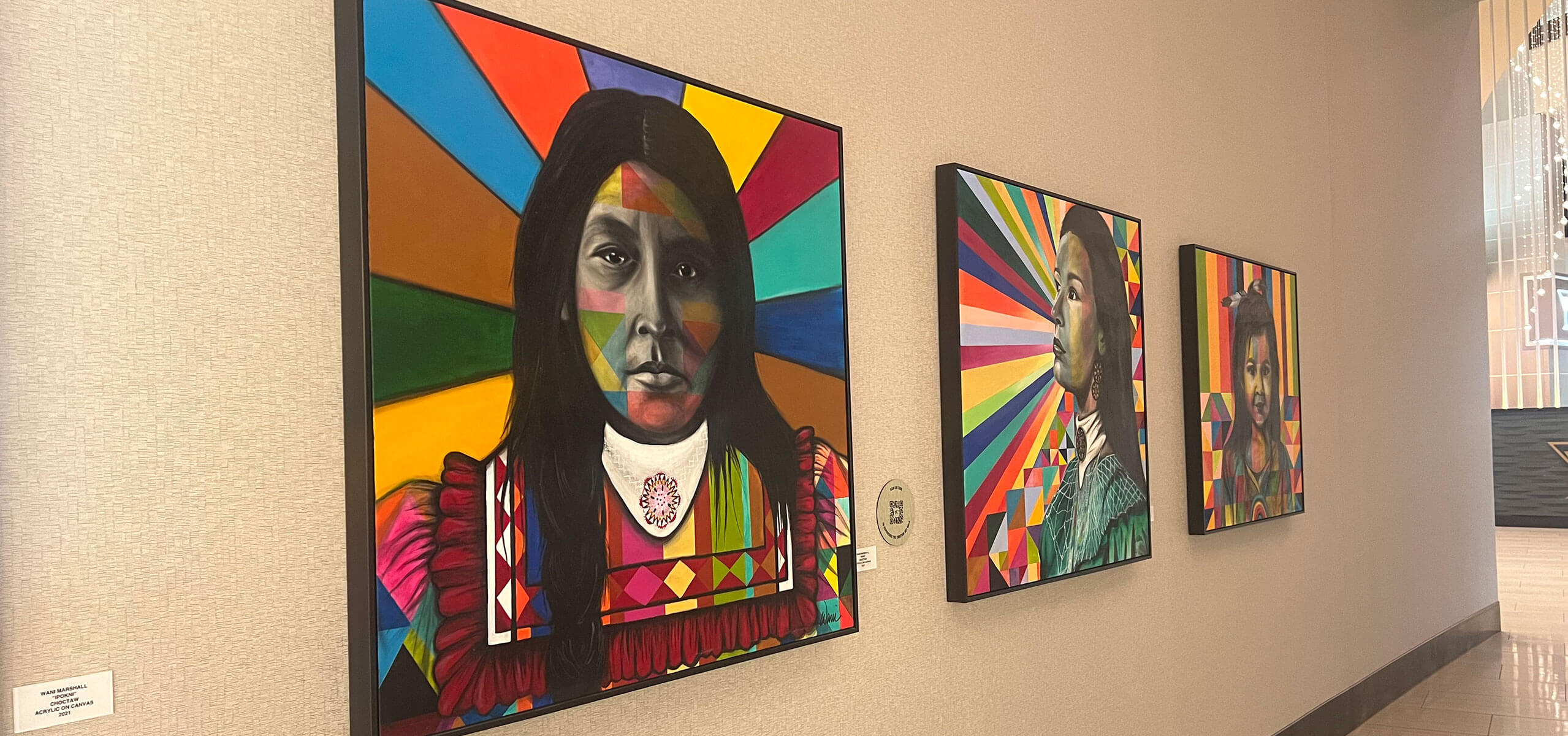 Hallway gallery inside the Art Gallery at Choctaw Casino & Resort Durant with three bright geometric portraits of Native American women