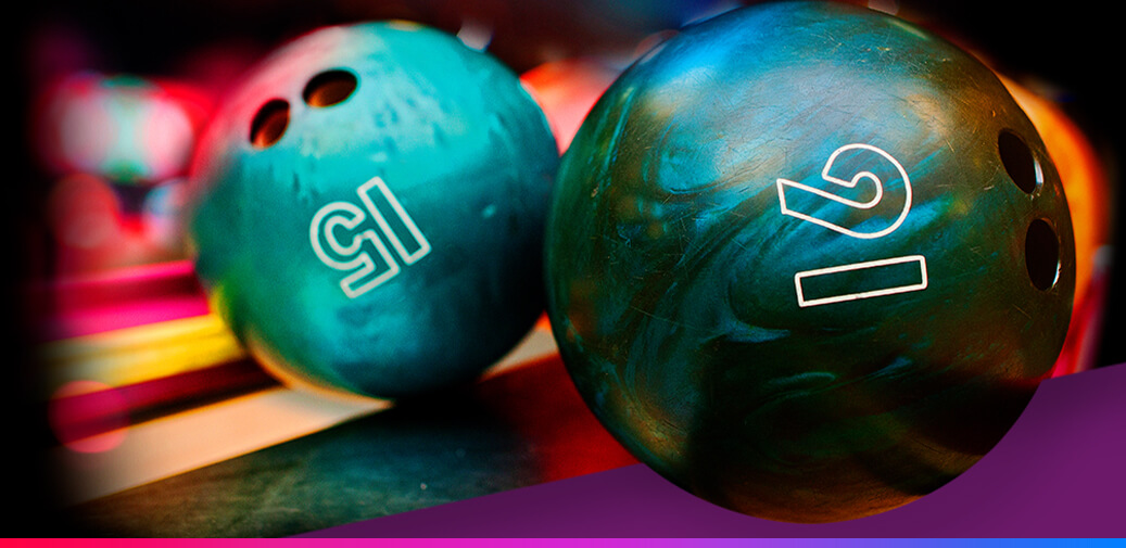 Close-up of two numbered bowling balls on a ball return.